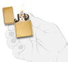 Widok z przodu zapalniczka Zippo Vintage Brass Brushed z ozdobnymi ukośnymi kreskami w obu narożnikach otwarta z płomieniem w stylizowanej dłoni