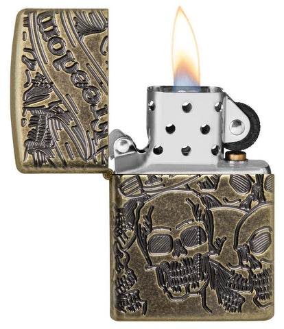Zapalniczka Zippo antyczny mosiądz z głęboko grawerowanymi czaszkami otwarta z płomieniem