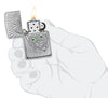 Zapalniczka Zippo kąt z głęboko grawerowaną czaszką z oczami z kryształków otwarta z płomieniem w stylizowanej dłoni